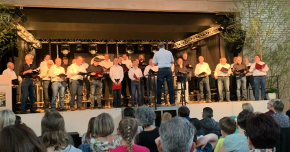 Die ganze Breite unseres Chors mit Mai-Schmuck vor Publikum in der Stadthalle Langenau